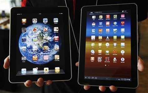 An employee of South Korean mobile carrier KT holds a Samsung Electronics' Galaxy Tab 10.1 tablet and Apple Inc's iPad tablet as he poses in An employee of South Korean mobile carrier KT holds a Samsung Electronics' Galaxy Tab 10.1 tablet and Apple Inc's iPad tablet as he poses in