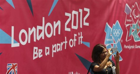 A woman takes a photo in front of a banner showcasing the London 2012 Olympics near Britain's embassy in Jakarta A woman takes a photo in front of a banner showcasing the London 2012 Olympics near Britain's embassy in Jakarta
