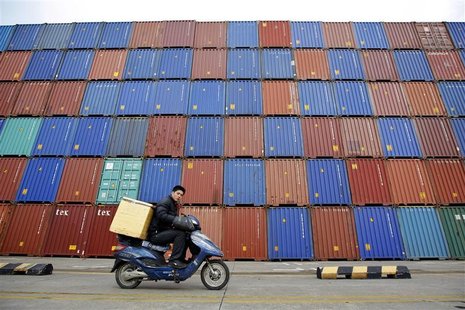 A man rides his motorcycle past shipping containers at the Port of Shanghai A man rides his motorcycle past shipping containers at the Port of Shanghai