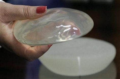An employee of the Ministry of Health displays a silicone gel breast implant, manufactured by the now-defunct French firm PIP, during a news An employee of the Ministry of Health displays a silicone gel breast implant, manufactured by the now-defunct French firm PIP, during a news