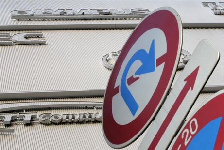 The logo of Olympus is seen behind traffic signs outside an electronic shop in Tokyo The logo of Olympus is seen behind traffic signs outside an electronic shop in Tokyo