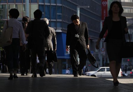 A man looks down as he walks through a financial district in Tokyo A man looks down as he walks through a financial district in Tokyo