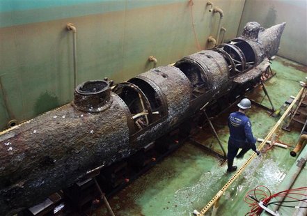 A member of the conservation crew walks beside the Civil War submarine H.L. Hunley as it now stands free of the steel truss that was used to A member of the conservation crew walks beside the Civil War submarine H.L. Hunley as it now stands free of the steel truss that was used to