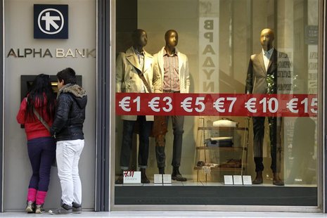 People make a transaction at an ATM during the first day of the official sales season in Athens People make a transaction at an ATM during the first day of the official sales season in Athens