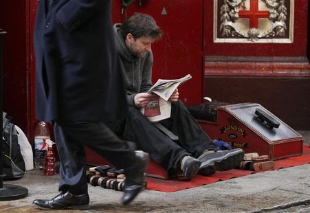 A pedestrian passes a man sat waiting at a shoe shine stall in the City of London A pedestrian passes a man sat waiting at a shoe shine stall in the City of London