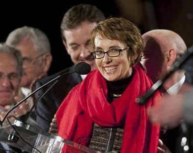 Arizona Representative Gabrielle Giffords (C), who suffered a head wound in the Tuscon shooting, smiles after reciting the Pledge of Allegiance at a memorial service marking the anniversary of the shooting, at the University of Arizona campus January 8, 2012. REUTERS/Laura Segall Arizona Representative Gabrielle Giffords (C), who suffered a head wound in the Tuscon shooting, smiles after reciting the Pledge of Allegiance at a memorial service marking the anniversary of the shooting, at the University of Arizona campus January 8, 2012. REUTERS/Laura Segall