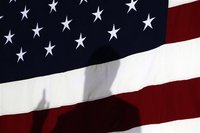 Republican presidential candidate and former Speaker of the House Newt Gingrich is silhouetted against the U.S. Flag during his speech at a 