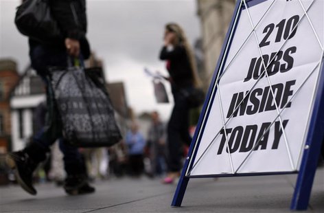 Shoppers walk past a newspaper advertising board promoting its job supplement in Leicester, central England Shoppers walk past a newspaper advertising board promoting its job supplement in Leicester, central England