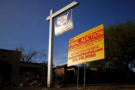 A realtor and bank-owned sign is displayed near a house for sale in Phoenix A realtor and bank-owned sign is displayed near a house for sale in Phoenix