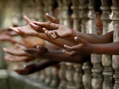 Homeless children reach out from behind a fence as they wait to collect free clothes at a local charity in the northeastern Indian city of S Homeless children reach out from behind a fence as they wait to collect free clothes at a local charity in the northeastern Indian city of S