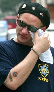 A man wearing a t-shirt from the New York Police Department pays his respects outside the U.S. Embassy in London, September 11, 2003 on the 