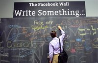An employee writes a note on the message board at the new headquarters of Facebook in Menlo Park