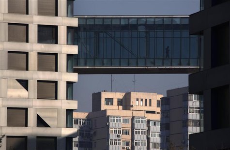 A man walks across a pedestrian bridge joining two residential apartment buildings in central Beijing A man walks across a pedestrian bridge joining two residential apartment buildings in central Beijing