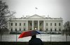 A man uses an umbrella as shelter from the snow in front of the White House in Washington