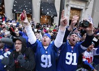 People celebrate during the New York Giants ticker tape Super Bowl victory parade through the Canyon of Heroes along Broadway in New York
