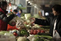 A customer pays for her vegetables at a market in Beijing