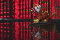 A toy dragon decoration for the upcoming Chinese Lunar New Year is seen in front of an electrical board showing stock information at a broke