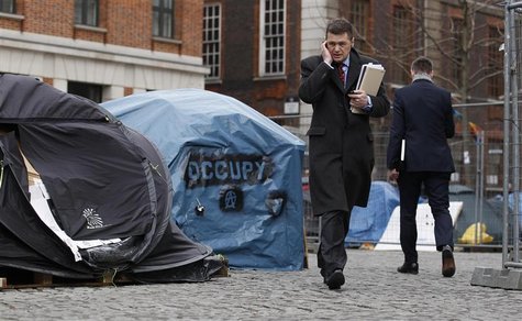 A pedestrian talks on the phone as he walks past tents in the Occupy London encampment outside St. Paul's Cathedral in London A pedestrian talks on the phone as he walks past tents in the Occupy London encampment outside St. Paul's Cathedral in London