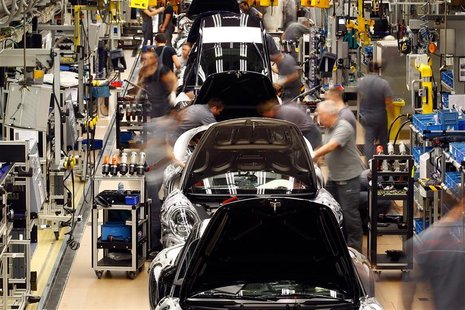 Workers assemble cars at a factory Workers assemble cars at a factory