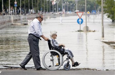 A man pushes his wheelchair-bound mother along the river bank of the flooded Danube river in Budapest A man pushes his wheelchair-bound mother along the river bank of the flooded Danube river in Budapest