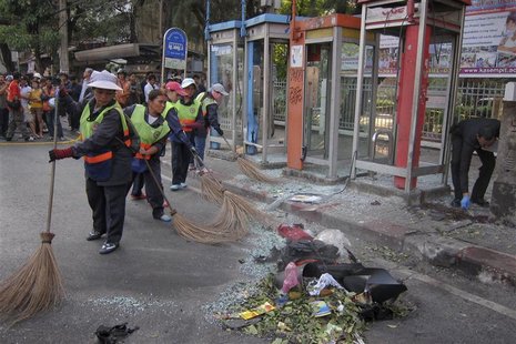 Cleaners sweep the road as police and forensic experts investigate the site where a man was injured when a bomb he was carrying exploded, in Cleaners sweep the road as police and forensic experts investigate the site where a man was injured when a bomb he was carrying exploded, in