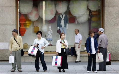 People wait for a bus to arrive in front of a shop window at a department store in Tokyo People wait for a bus to arrive in front of a shop window at a department store in Tokyo