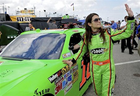 NASCAR Sprint Cup Series driver Danica Patrick (R) waves to fans while rolling her number 10 car out to the track before a practice session 