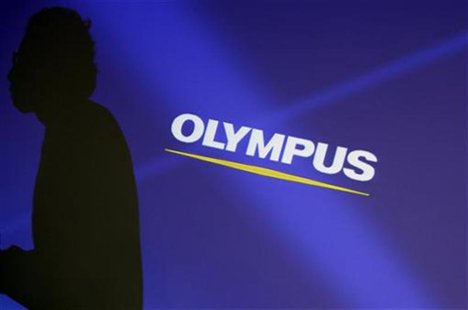 Staff member is silhouetted on a projector screen displaying a logo of Olympus Corp before a news conference in Tokyo Staff member is silhouetted on a projector screen displaying a logo of Olympus Corp before a news conference in Tokyo