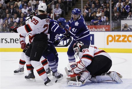 Devils' Brodeur makes a save behind teammate Fayne against Maple Leafs' Kulemin and MacAruther during their NHL hockey game in Toronto