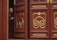 A Buddhist monk looks from behind a door before worship during the Tibetan New Year celebrations at Yonghegong Lama Temple in Beijing