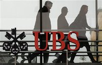 People walk behind the logo of Swiss bank UBS in Zurich