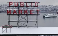 Snow blankets the roof of the famous Pike Place Market as a ferry floats past in Seattle