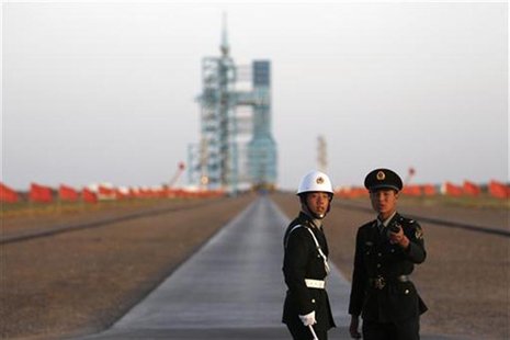 Soldiers stand in front of the Long March II-F rocket loaded with China's unmanned space module Tiangong-1 before its planned launch from th Soldiers stand in front of the Long March II-F rocket loaded with China's unmanned space module Tiangong-1 before its planned launch from th
