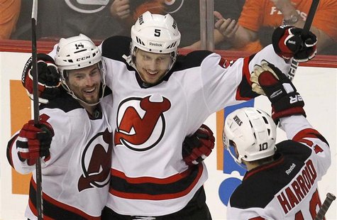 New Jersey Devils' Adam Larsson (C) celebrates with teammates Peter Harrold (R) and Adam Henrique during the third period in Game 2 of their New Jersey Devils' Adam Larsson (C) celebrates with teammates Peter Harrold (R) and Adam Henrique during the third period in Game 2 of their