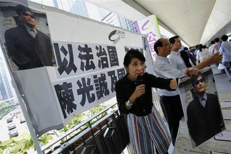 A member from the pro-democracy Civic Party displays a photograph of blind Chinese activist Chen Guangcheng to passersby during a campaign c A member from the pro-democracy Civic Party displays a photograph of blind Chinese activist Chen Guangcheng to passersby during a campaign c