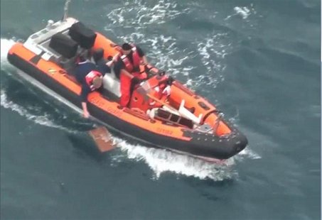 A member of the U.S. Coast Guard reaches for a piece of flotsam during their search for the lone missing crew member of the yacht Aegean off A member of the U.S. Coast Guard reaches for a piece of flotsam during their search for the lone missing crew member of the yacht Aegean off