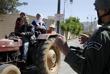 A family riding on a tractor pass a Syrian soldier at a checkpoint, during a field visit made by United Nations (U.N.) observers to the Mada A family riding on a tractor pass a Syrian soldier at a checkpoint, during a field visit made by United Nations (U.N.) observers to the Mada