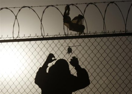 A man watches a U.S. border patrol helicopter from a fence at the border between Mexico and the United States, in Ciudad Juarez March 8, 201 A man watches a U.S. border patrol helicopter from a fence at the border between Mexico and the United States, in Ciudad Juarez March 8, 201