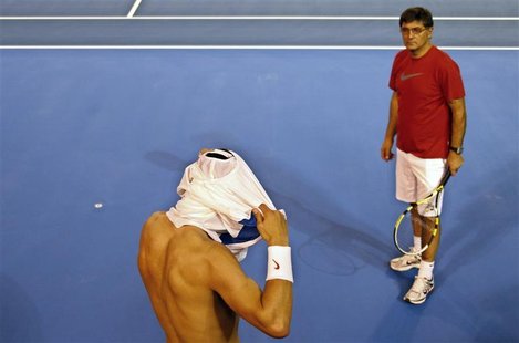 Rafael Nadal of Spain changes his shirt as his coach and uncle Toni Nadal watches during a training session at Melbourne Park January 13, 20 Rafael Nadal of Spain changes his shirt as his coach and uncle Toni Nadal watches during a training session at Melbourne Park January 13, 20