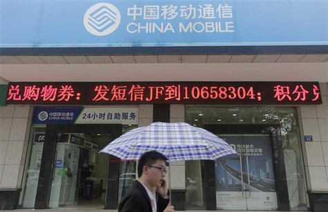 A man walks past a branch of China Mobile as he talks on his mobile phone on a rainy day in Wuhan, Hubei province April 20, 2012. REUTERS/St A man walks past a branch of China Mobile as he talks on his mobile phone on a rainy day in Wuhan, Hubei province April 20, 2012. REUTERS/St