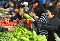 A customer (R) bargains with a vendor for eggplants at an open-air food market in Shenyang, Liaoning province May 11, 2012. REUTERS/Sheng Li