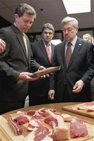 Kansas Governor Sam Brownback (L), Texas Governor Rick Perry (C) and Iowa Governor Terry Branstad (R) examine a package of the beef product 