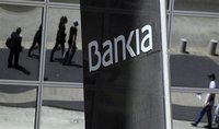 Pedestrians are reflected in the Bankia headquarters building in Madrid, May 10, 2012. REUTERS/Paul Hanna