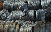 A labourer walks on coils of steel wire at a steel market in Shenyang, Liaoning province April 13, 2012. REUTERS/Sheng Li