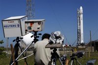 News photographers work on their remote cameras as the SpaceX Falcon 9 test rocket is being prepared for a second launch attempt from Space 