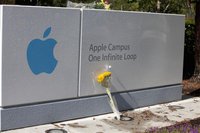 A bouquet of flowers in honor of the passing of former Apple CEO Steve Jobs lies in front of the sign of Apple headquarters in Cupertino, Ca