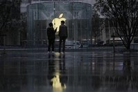Two men stand in front of an Apple logo outside an Apple store in Shanghai February 22, 2012. REUTERS/Aly Song