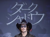 Actor Johnny Depp poses in front of a screen showing the name of the film in Japanese during a photo call at a news conference for their fil