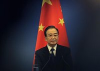 China's Premier Wen Jiabao stands in front of a Chinese national flag as he attends a joint news conference of the fifth trilateral summit a