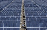 An employee walks between rows of solar panels at a solar power plant on the outskirts of Dunhuang, Gansu province June 10, 2011. REUTERS/St